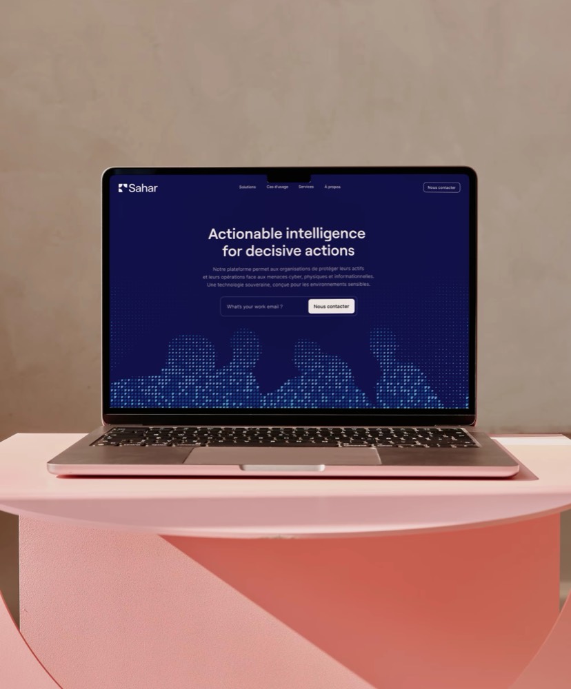 Landing page Sahar ouverte sur un portable posé sur un socle rose : titre « Actionable intelligence for decisive actions » et trame de points cobalt en pied de hero.