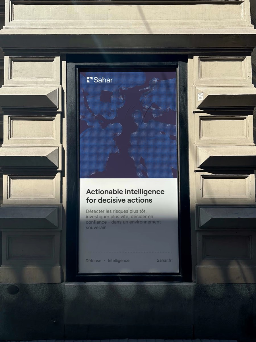 Poster Sahar dans une vitrine sur une façade en pierre : trame de points cobalt en haut, bandeau blanc en bas avec le titre « Actionable intelligence for decisive actions ».